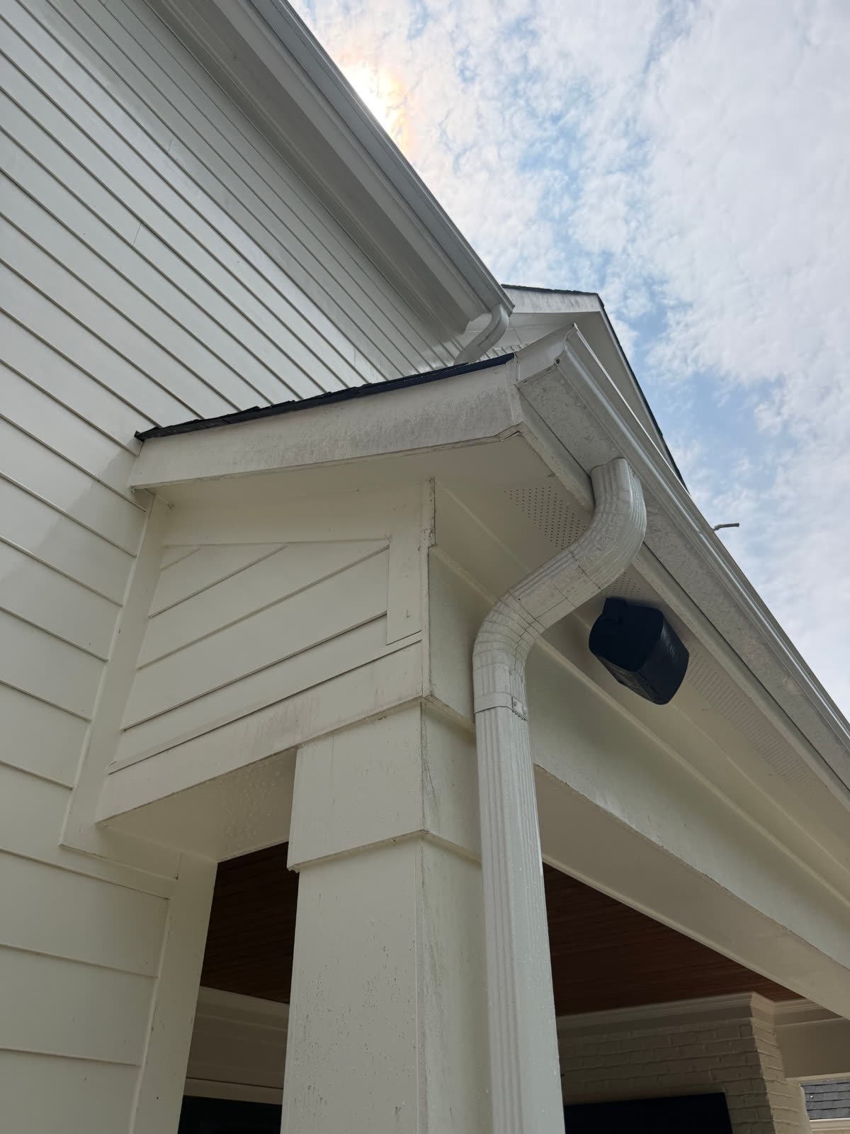 Gutter corner, downspout, and soffit before and after a soft wash — before