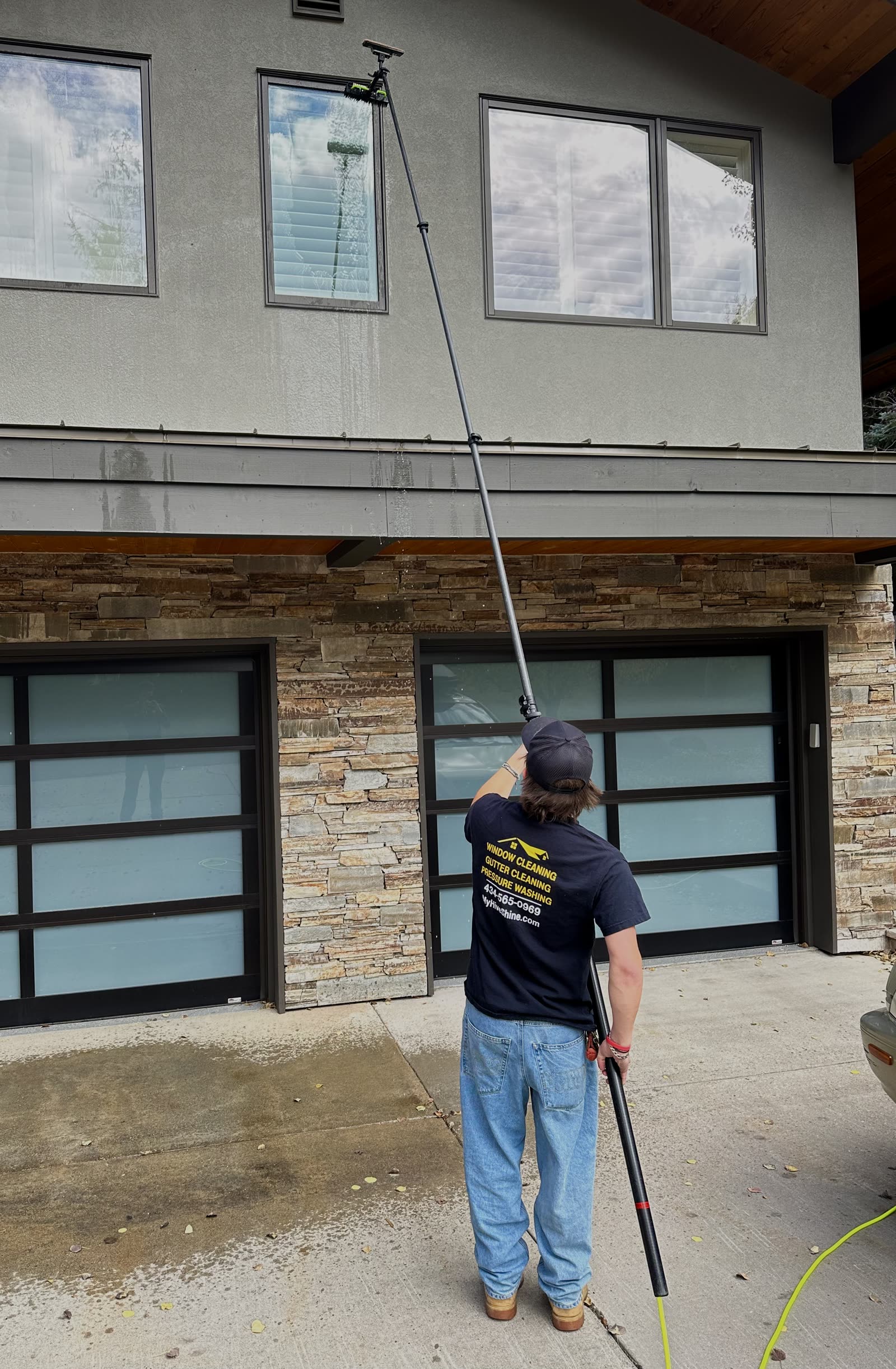 Technician cleaning upper-story windows with a water-fed pole