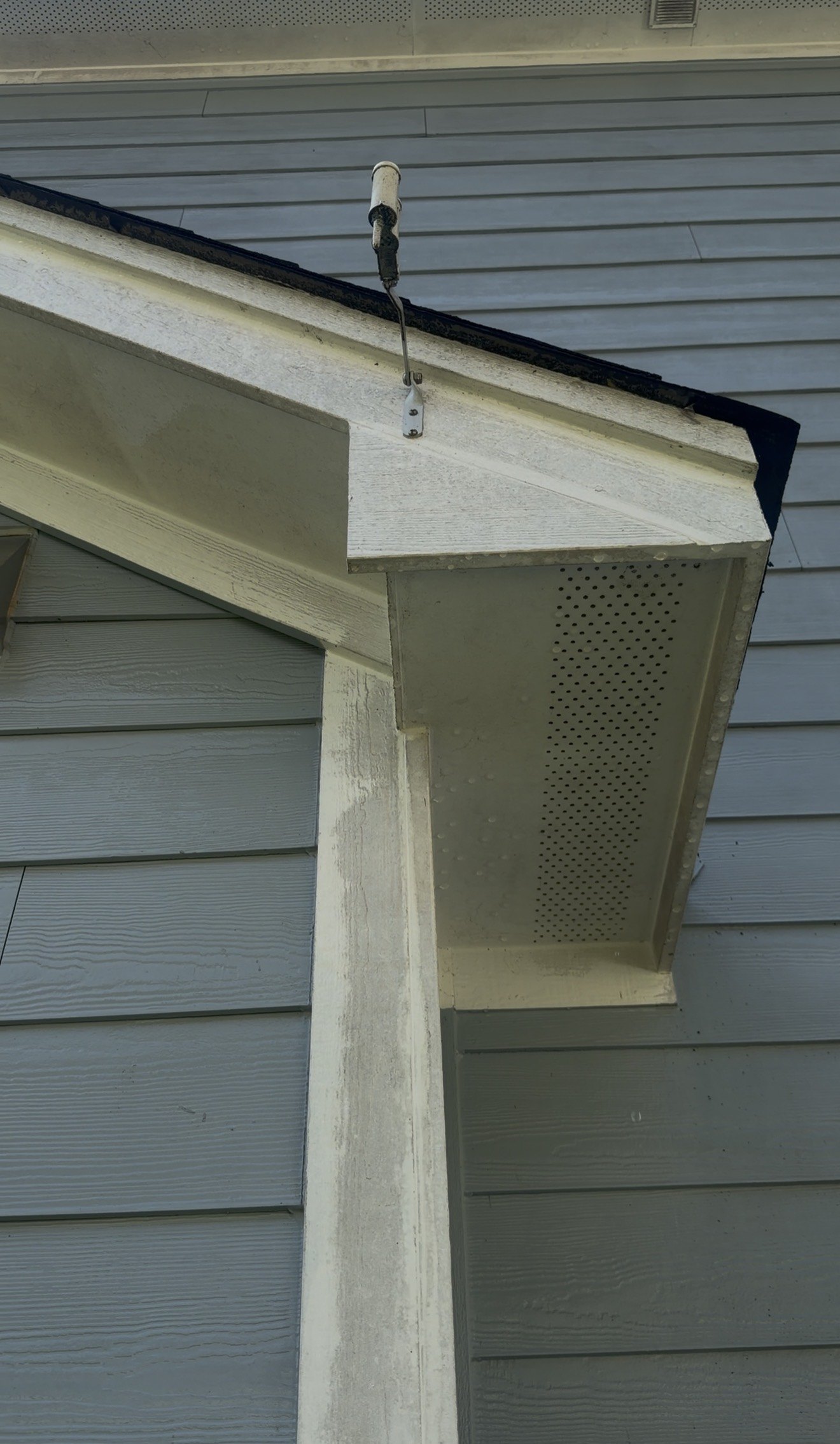 White entry fascia, trim, and perforated soffit before and after removal of dark organic buildup — before