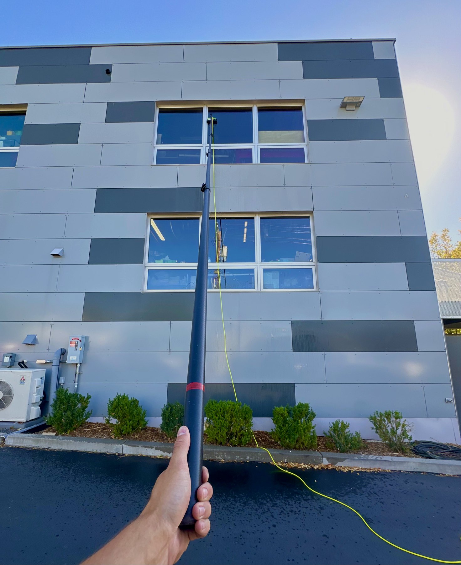 Water-fed pole reaching upper windows on a commercial building