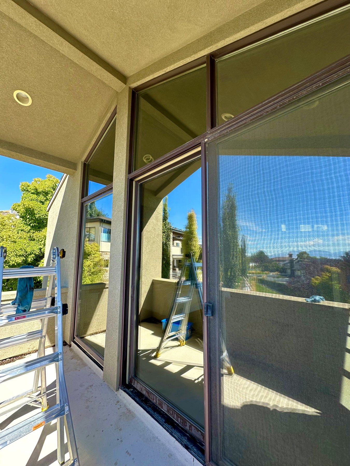 Ladder set up beside tall glass doors during an exterior cleaning job