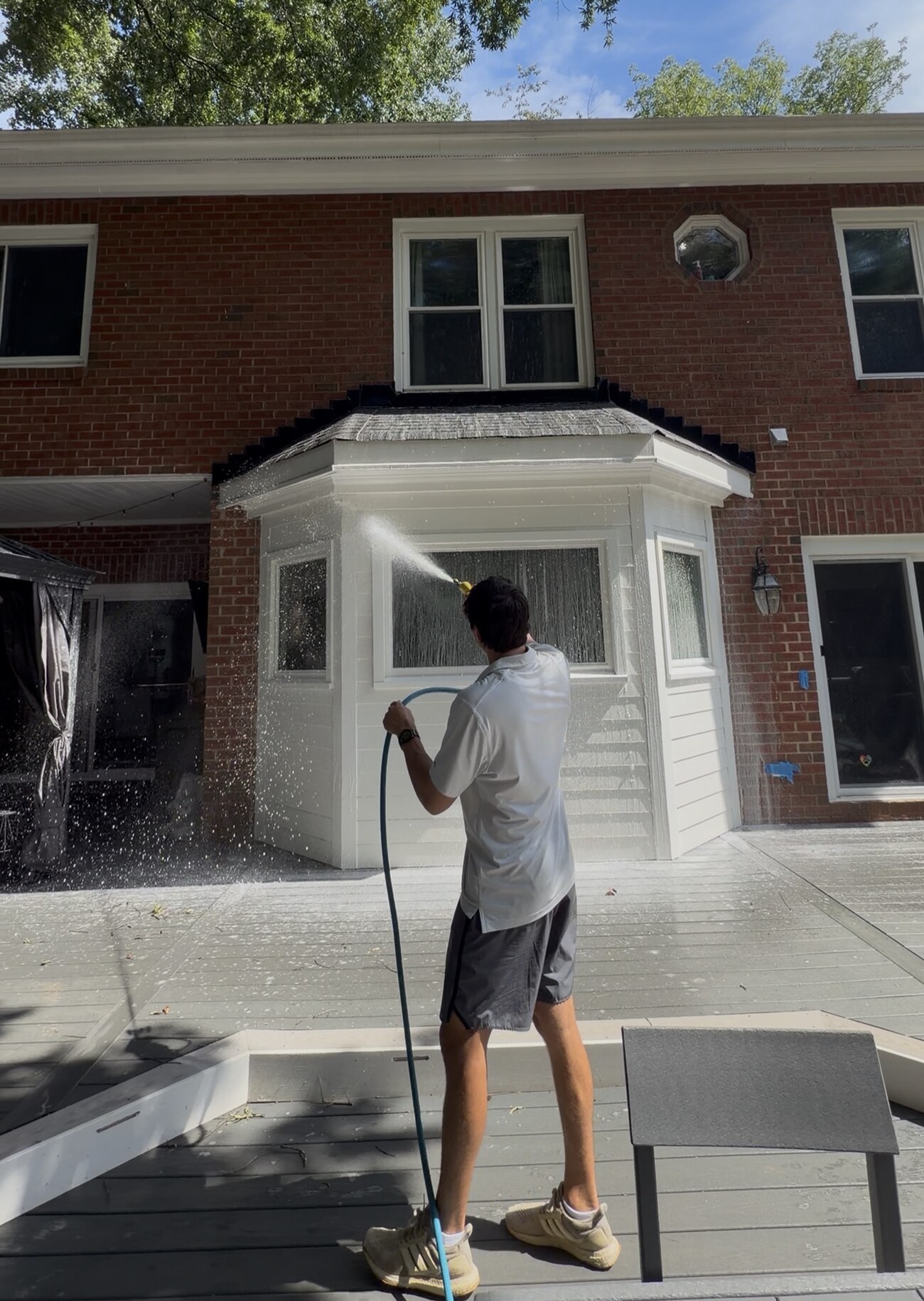 Calvin Dornan of Tradition Exteriors rinsing a bay window during a house wash in Charlotte