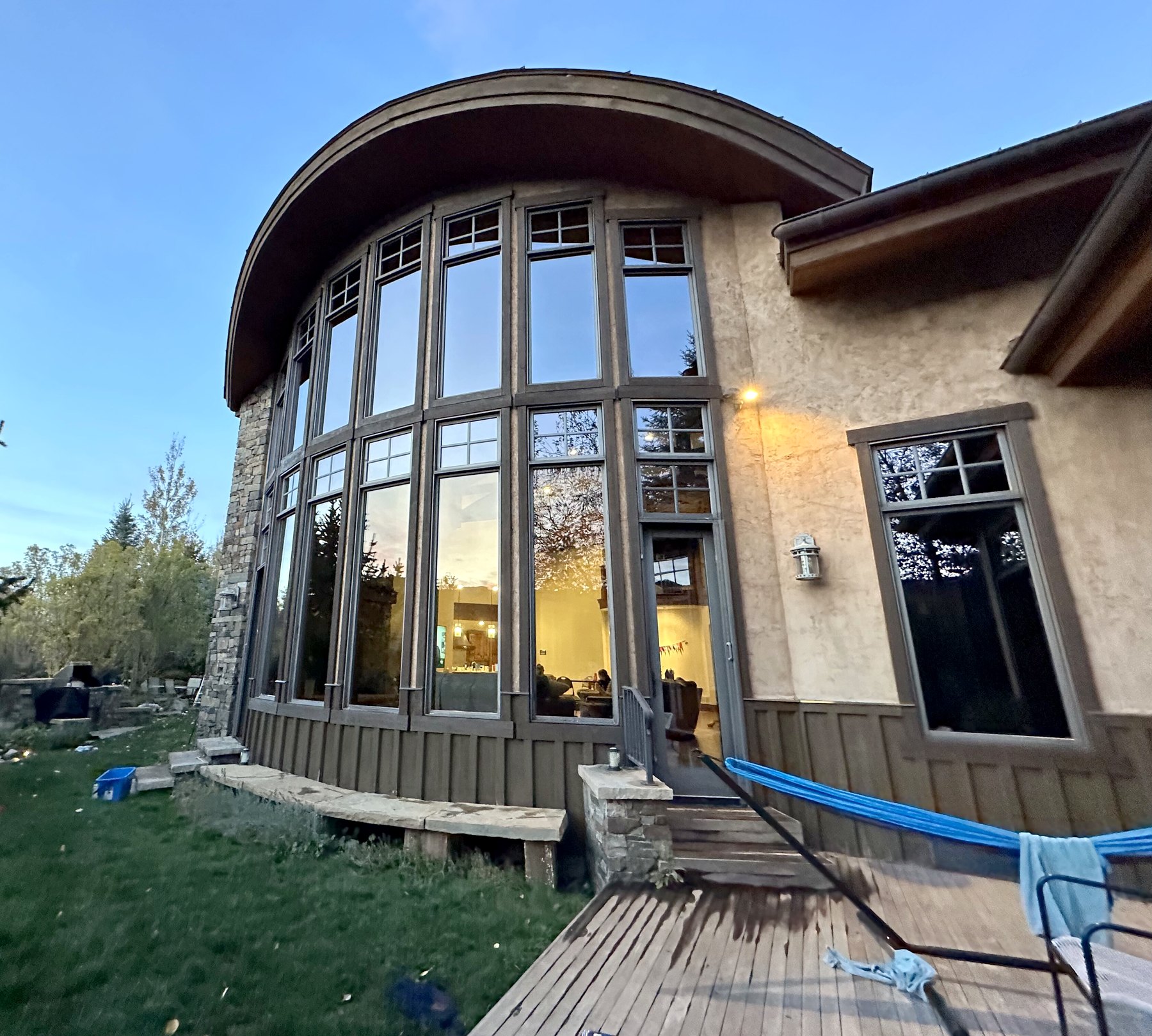 Large curved window wall on a stone and stucco home at dusk
